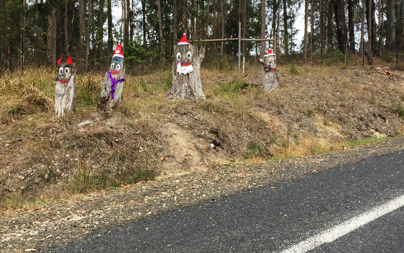 Roadside tree stumps decorated as a family of santa's, elves and reindeers